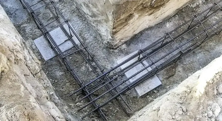 Zbrojenie płyty fundamentowej w wykopie. Stalowe pręty tworzą siatkę, gotową na zalanie betonem.