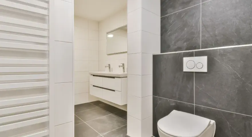 Salle de bain moderne avec wc suspendu, carrelage gris anthracite et blanc, lavabo suspendu et radiateur blanc.