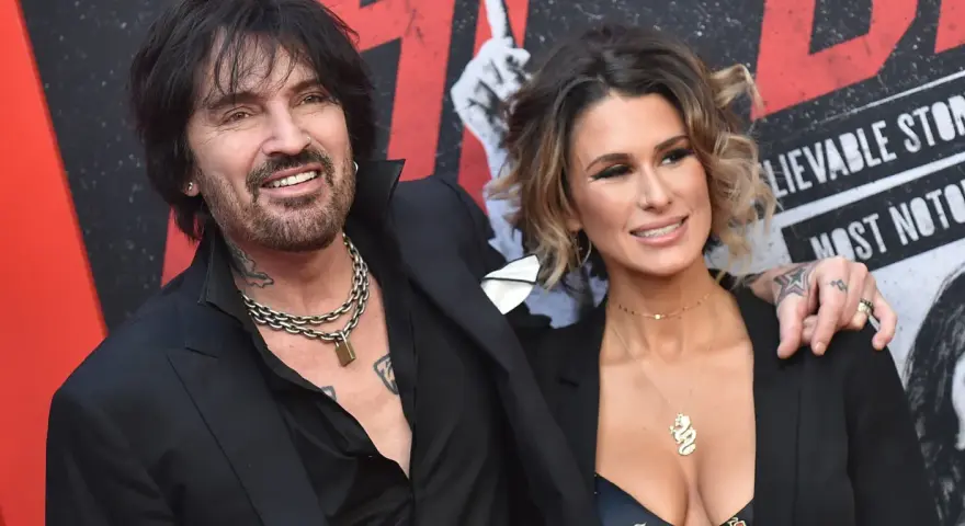 Tommy Lee i jego żona, Brittany Furlan, uśmiechają się do aparatu na czerwonym dywanie.