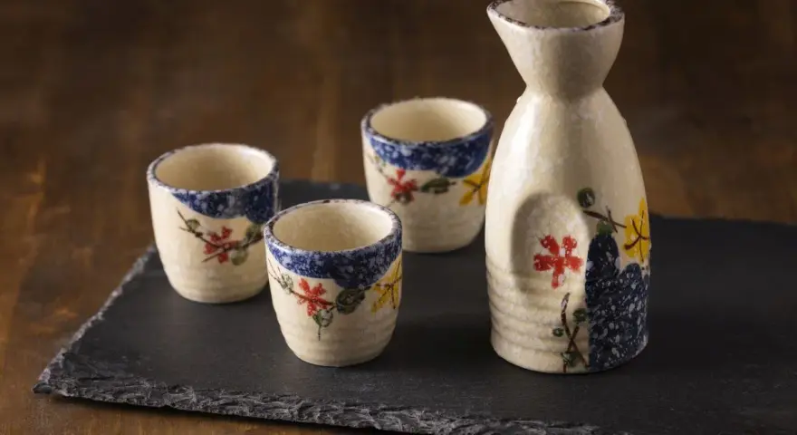 Zestaw do sake z ceramicznym dzbankiem i trzema kieliszkami, ozdobiony motywem kwiatowym. Idealny do degustacji sake, niezależnie od tego, sake ile procent ma zawartości alkoholu.