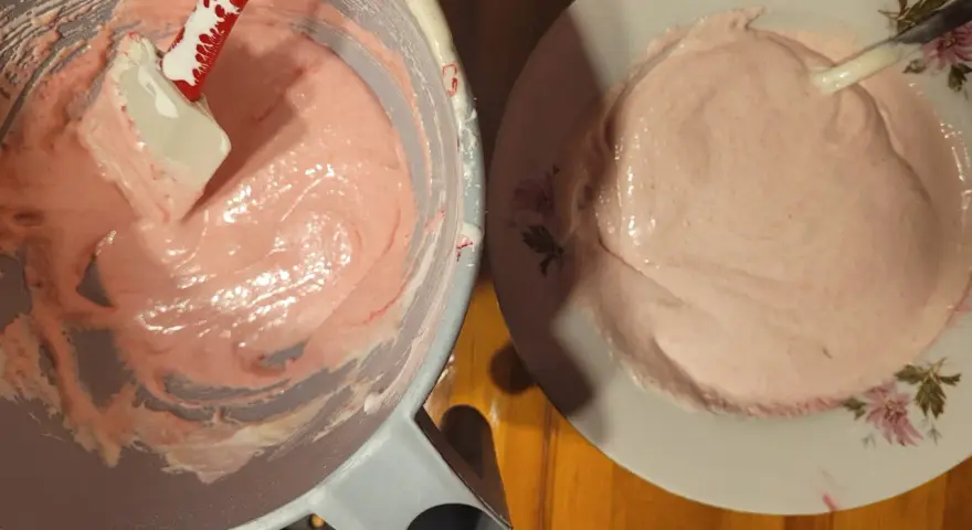 Różowa masa na makaroniki w misce i na talerzyku. Szpatułka miesza kremową konsystencję. Idealny makaroniki przepis w przygotowaniu.