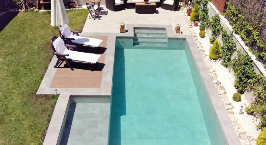 Un jardín con piscinas modernas, tumbonas, zona de estar y barbacoa.