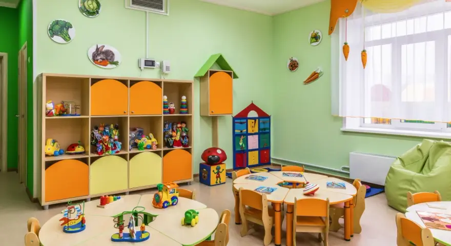 Kolorowa sala przedszkolna z zabawkami i stolikami. Zastanawiasz się, ile kosztuje żłobek? To miejsce wygląda na przyjazne dla dzieci.