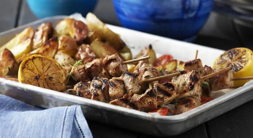 Grillade souvlaki-spett med rostade potatisar och citronklyftor. Ett perfekt souvlaki recept för en härlig middag.