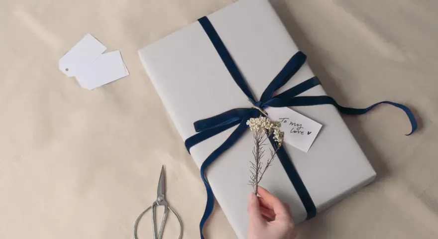 Prezent na 8 rocznicę ślubu, owinięty w szary papier i ozdobiony granatową aksamitną wstążką. Drobna gałązka i karteczka "To my love" dodają uroku.