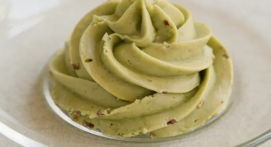 Puszysty krem pistacjowy do tortu, udekorowany na talerzyku.