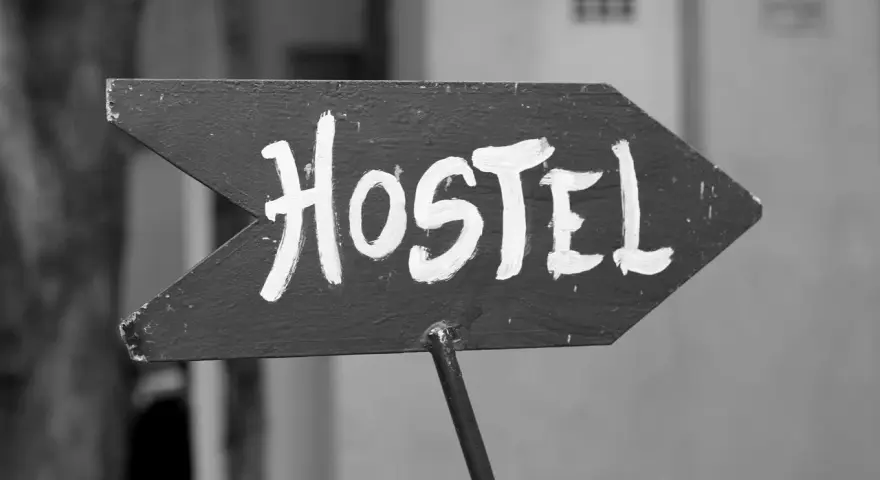 Strzałka z napisem "Hostel" wzywa podróżnych do taniego noclegu. To miejsce, gdzie poznasz innych wędrowców.