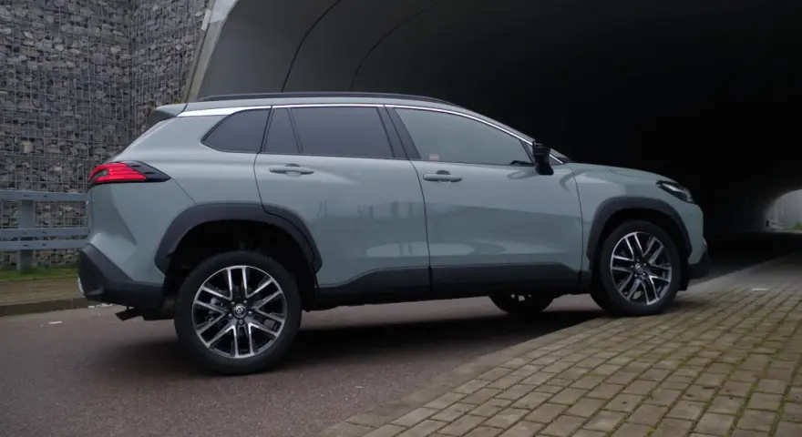 Szary Toyota Corolla Cross hybrydowa stoi na tle tunelu.