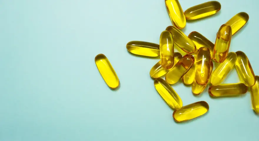 En hög med genomskinliga, gulaktiga kapslar som innehåller alla vitaminer.