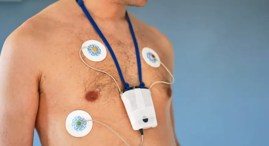 Mężczyzna z elektrodami EKG na klatce piersiowej i urządzeniem do badania holtera. Unikaj wysiłku fizycznego podczas badania holtera.