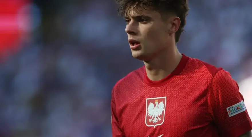 Młody piłkarz w czerwonej koszulce z orłem, symbolizujący polską reprezentację. Jego wzrost i determinacja na boisku budzą nadzieję na przyszłe sukcesy.