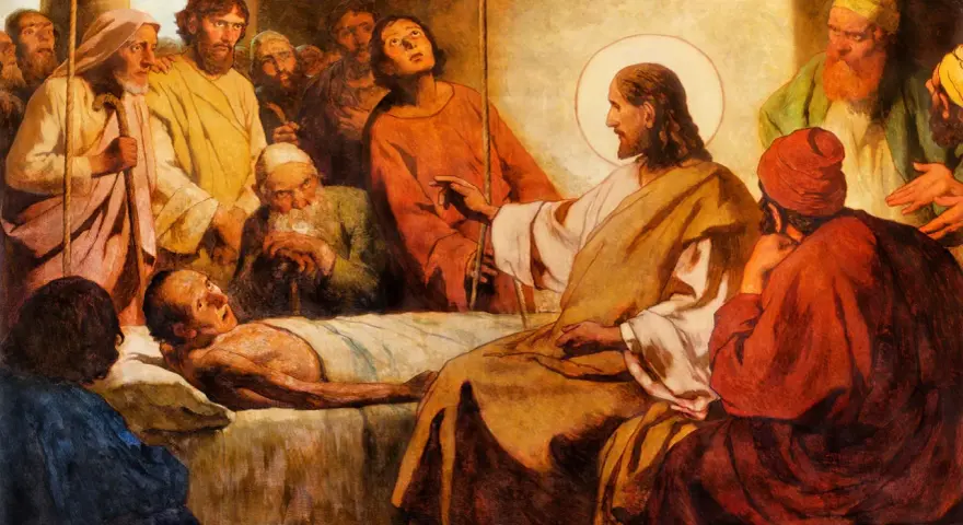 Jesus with a halo touches a sick man lying in bed, surrounded by onlookers.