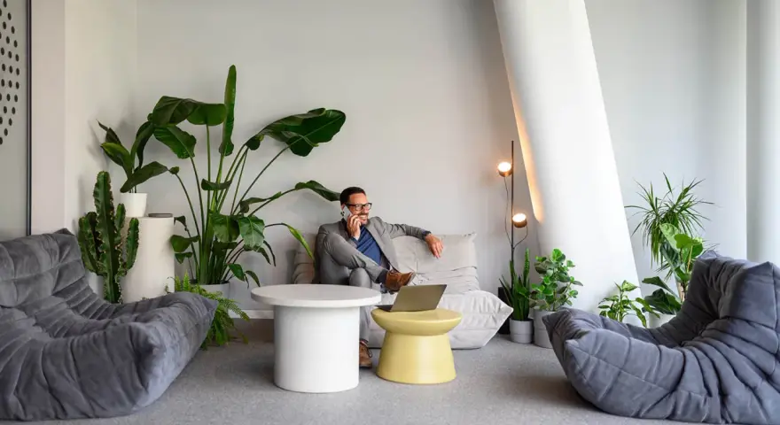 Un homme d'affaires au téléphone dans un coin salon moderne avec des plantes, une idée pour optimiser petit espace.