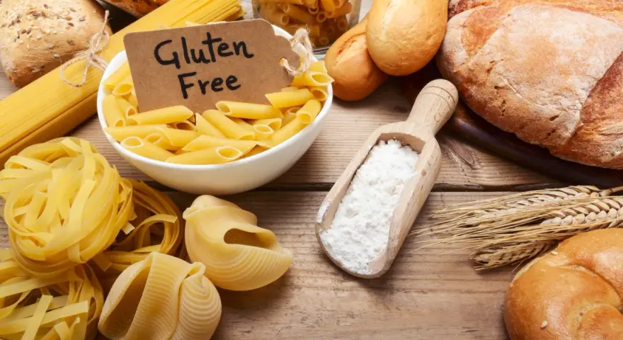Miesiąc bez glutenu efekty: makarony, pieczywo i mąka na drewnianym stole.