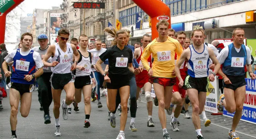 Löpare i en maratonlopp, många med nummerbrickor. En kvinna springer i mitten.