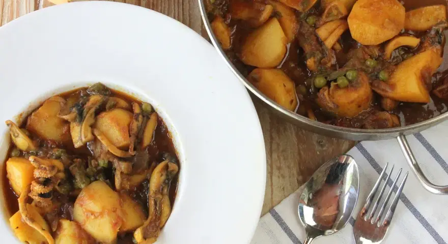Plato de papas con choco y guisantes en salsa. Un delicioso guiso casero listo para servir.