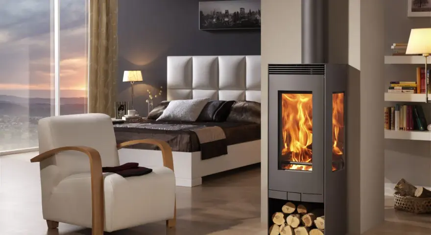 Acogedora habitación con cama, sillón y estufas esquineras modernas que irradian calor.