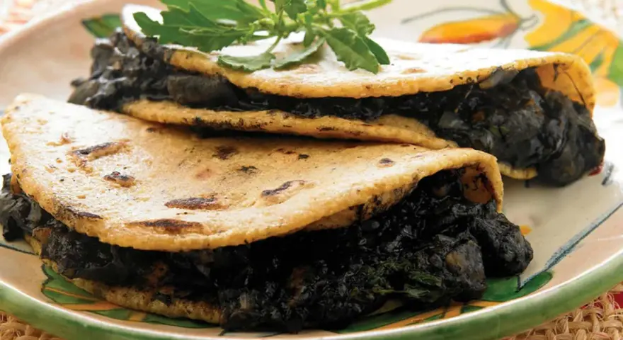 Dos tortillas de maíz rellenas de quelites, un platillo que evoca lo que comían los aztecas.