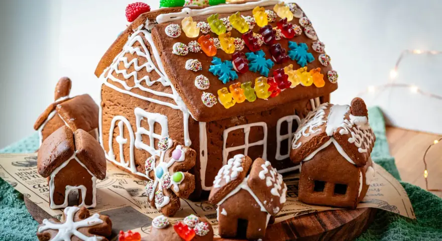 Kreative Ideen für ein Lebkuchenhaus: Ein detailreiches Lebkuchenhaus mit bunten Gummibärchen und kleinen Lebkuchenhäusern drumherum.