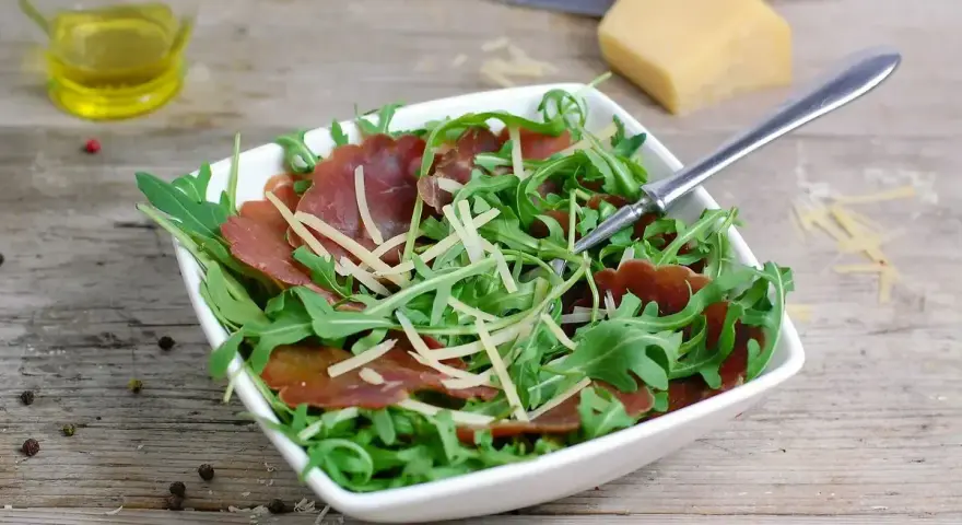 Insalata fresca con bresaola rucola e grana, condita con olio d'oliva e pepe.
