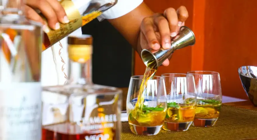 Barman nalewa cachacę do szklanek z lodem i miętą. To popularny brazylijski alkohol.