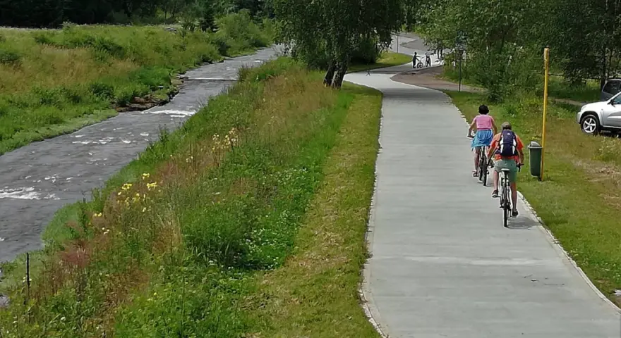 Rowerzyści cieszą się malowniczymi trasami rowerowymi w Muszynie, jadąc wzdłuż rzeki.