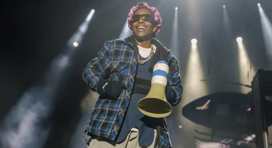 A$AP Rocky na koncercie w kręconych włosach i kratowanej koszuli, trzymający megafon.