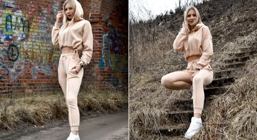 Dresy damskie szerokie w beżowym kolorze, idealne na co dzień. Modelka prezentuje je na tle ceglanej ściany i schodów.