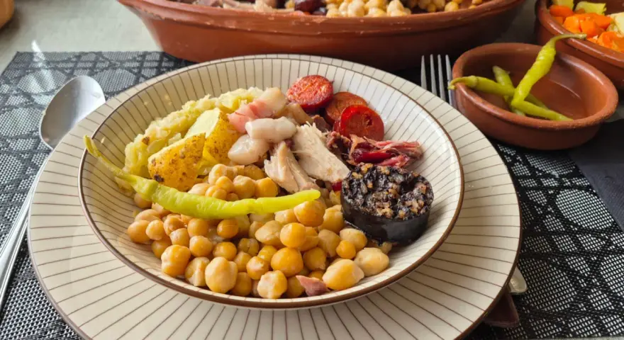 Plato de cocido con garbanzos, patatas, chorizo, morcilla y pimientos.