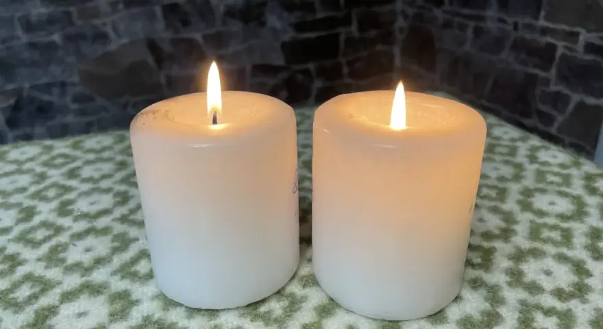 Two white candles glow softly, their flames flickering. This peaceful scene evokes the second Sunday of Advent theme of hope and preparation.