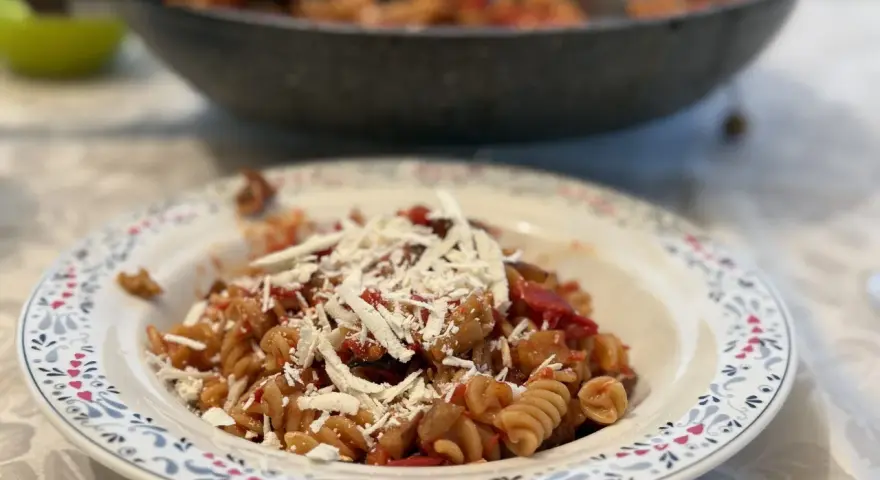 Plato de pasta alla norma con fusilli, berenjena, tomate y queso rallado, listo para disfrutar.