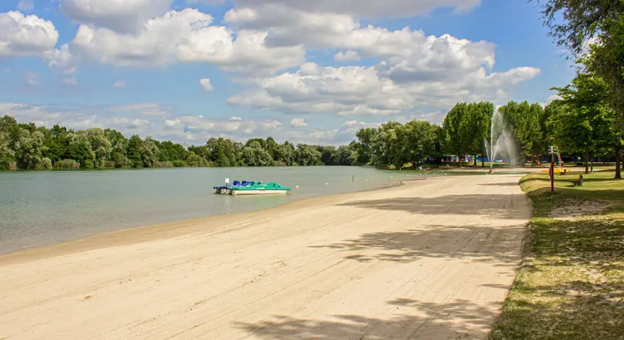Sommerliche Idylle am Baggersee: Sandstrand, Tretboote und eine Fontäne laden zum Entspannen ein. Hier lässt sich das Leben in Karlsruhe genießen.