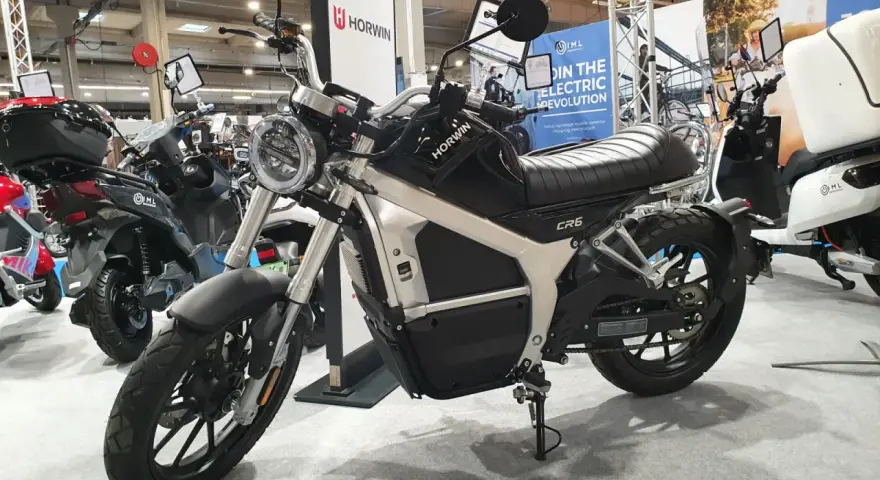Elegancki motocykl elektryczny Horwin CR6, idealny do zdobycia prawa jazdy na motocykl. W tle inne skutery elektryczne.