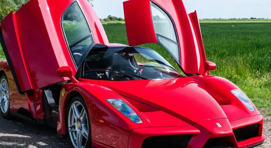 Czerwone Ferrari Enzo z otwartymi drzwiami, marzenie wielu. Zastanawiasz się, ferrari enzo ile kosztuje?