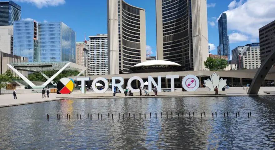 Toronto co zobaczyć: wielki napis TORONTO przed ratuszem miejskim, z fontanną i nowoczesnymi budynkami w tle.