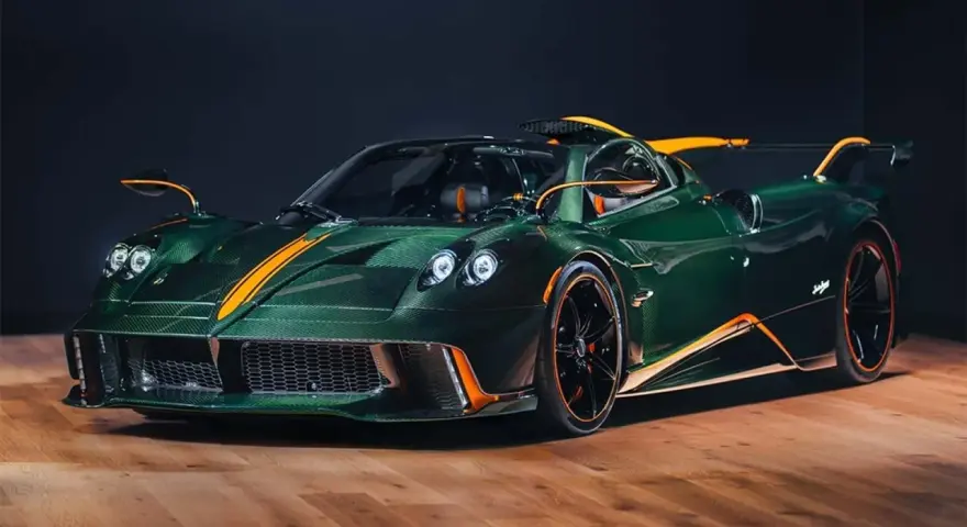 Pagani Huayra w kolorze głębokiej zieleni z pomarańczowymi akcentami, prezentuje swoje karbonowe nadwozie na drewnianej podłodze.