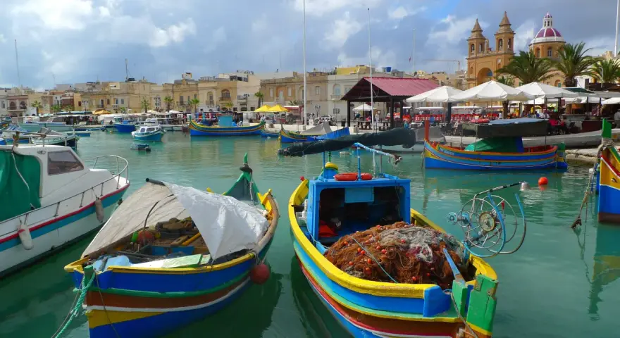 Kolorowe łodzie rybackie w porcie na Malcie, gdzie można poczuć klimat i zobaczyć, jak wygląda malta waluta w codziennym życiu.