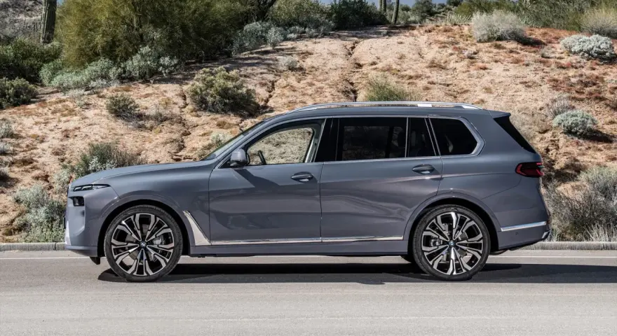 Szary BMW X9 na tle pustynnego krajobrazu. Elegancki SUV z chromowanymi detalami i masywnymi felgami.