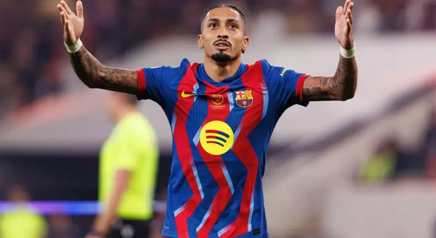 Raphinha, z podniesionymi rękami, świętuje po dołączeniu do FC Barcelony. Jego koszulka zdobi logo Spotify.