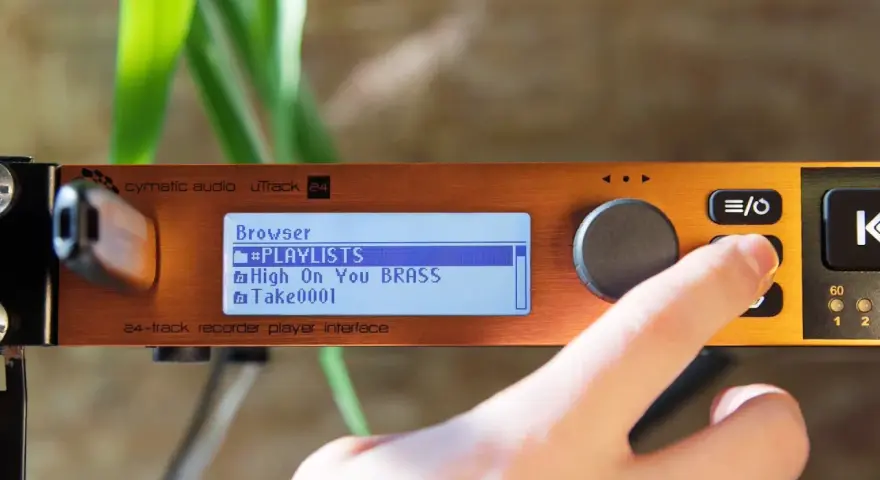 Palec naciska przycisk na urządzeniu cymatic audio uTrack 24, wyświetlającym listę odtwarzania.