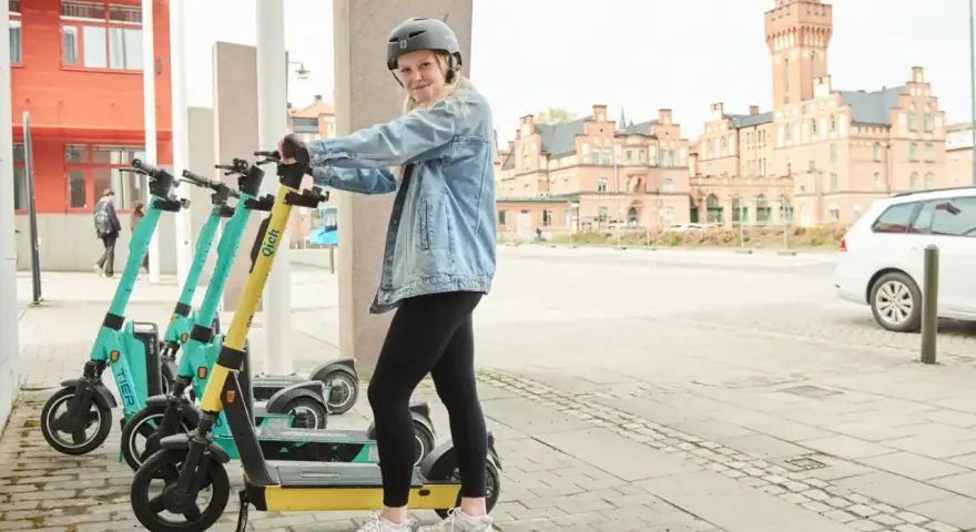 Tjej med hjälm redo att köra elsparkcykel. Tänk på elsparkcykel regler för en trygg resa.