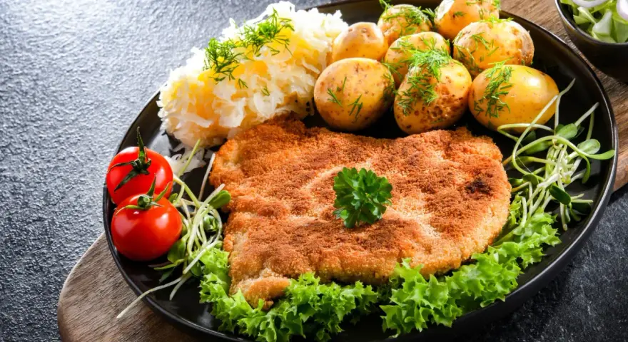 Idealny kotlet schabowy przepis: panierowany schab, ziemniaczki, surówka i pomidorki. Pyszny obiad!