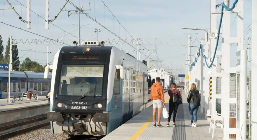 Pociąg na stacji z pasażerami czekającymi na peronie.