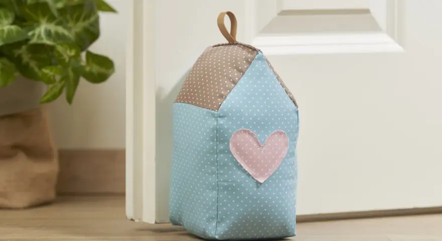 Un cale porte en tissu gratuit en forme de maison, avec un cœur rose. Parfait pour un **patron cale porte en tissu gratuit**.