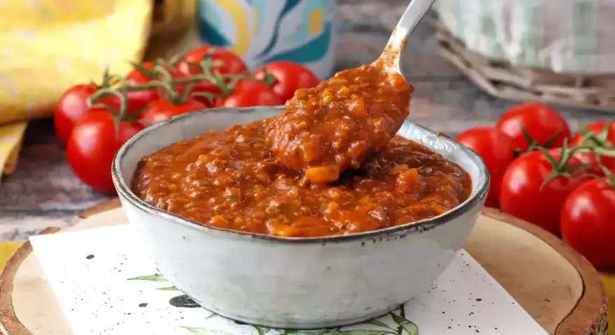 Gęsty, aromatyczny sos bolognese w misce, gotowy do podania. Obok świeże pomidory.
