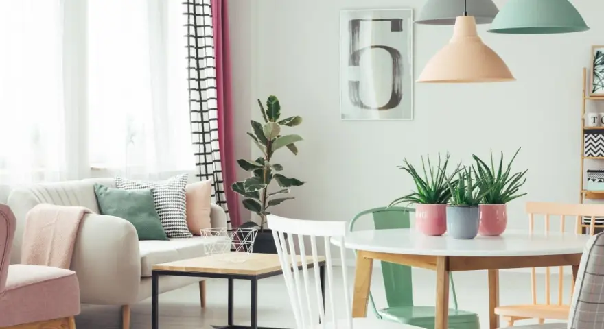 Jasne, oto opis:

Salon w stylu skandynawskim, gdzie dominują **kolory pastelowe**. Miękka sofa, różowe fotele i zielone akcenty tworzą przytulną atmosferę.