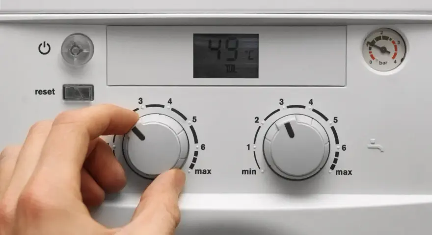 Mano che regola la caldaia spenta senza corrente. Il display mostra 49°C.