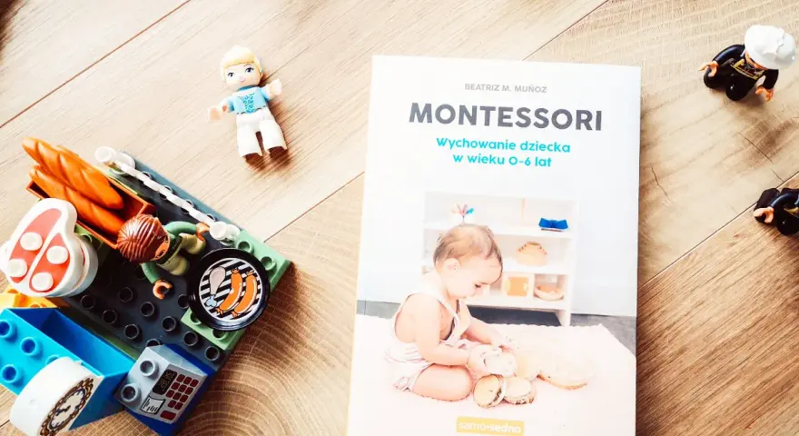 Książka "Montessori. Wychowanie dziecka w wieku 0-6 lat" obok klocków i figurek. Idealna do nauki przez zabawę.