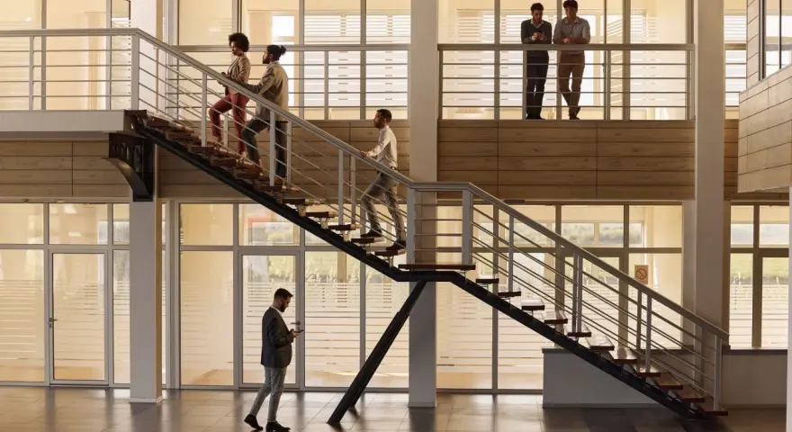 Personas subiendo escaleras, disfrutando de los beneficios de la actividad física en un moderno edificio de oficinas.
