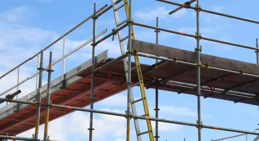 Rusztowanie aluminiowe z drabiną na tle błękitnego nieba.
